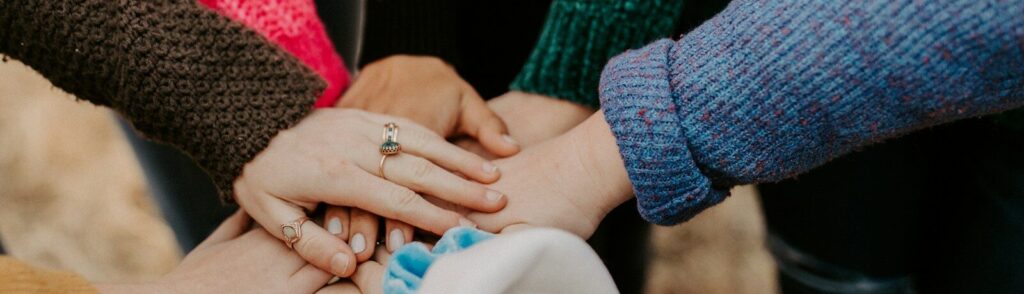 group stacking hands in colorful sweaters