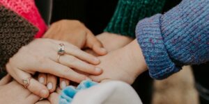 group stacking hands in colorful sweaters